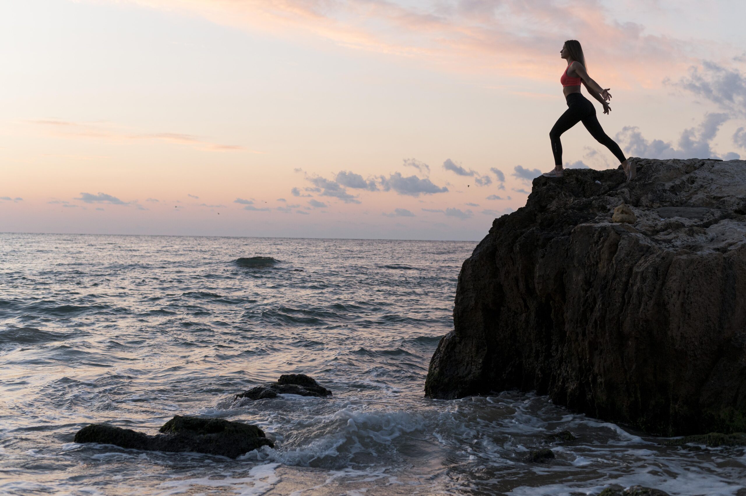 raise your vibration by feeling the morning energy, a woman standing on a mountaintop in a morning sunrise feeling high vibrations