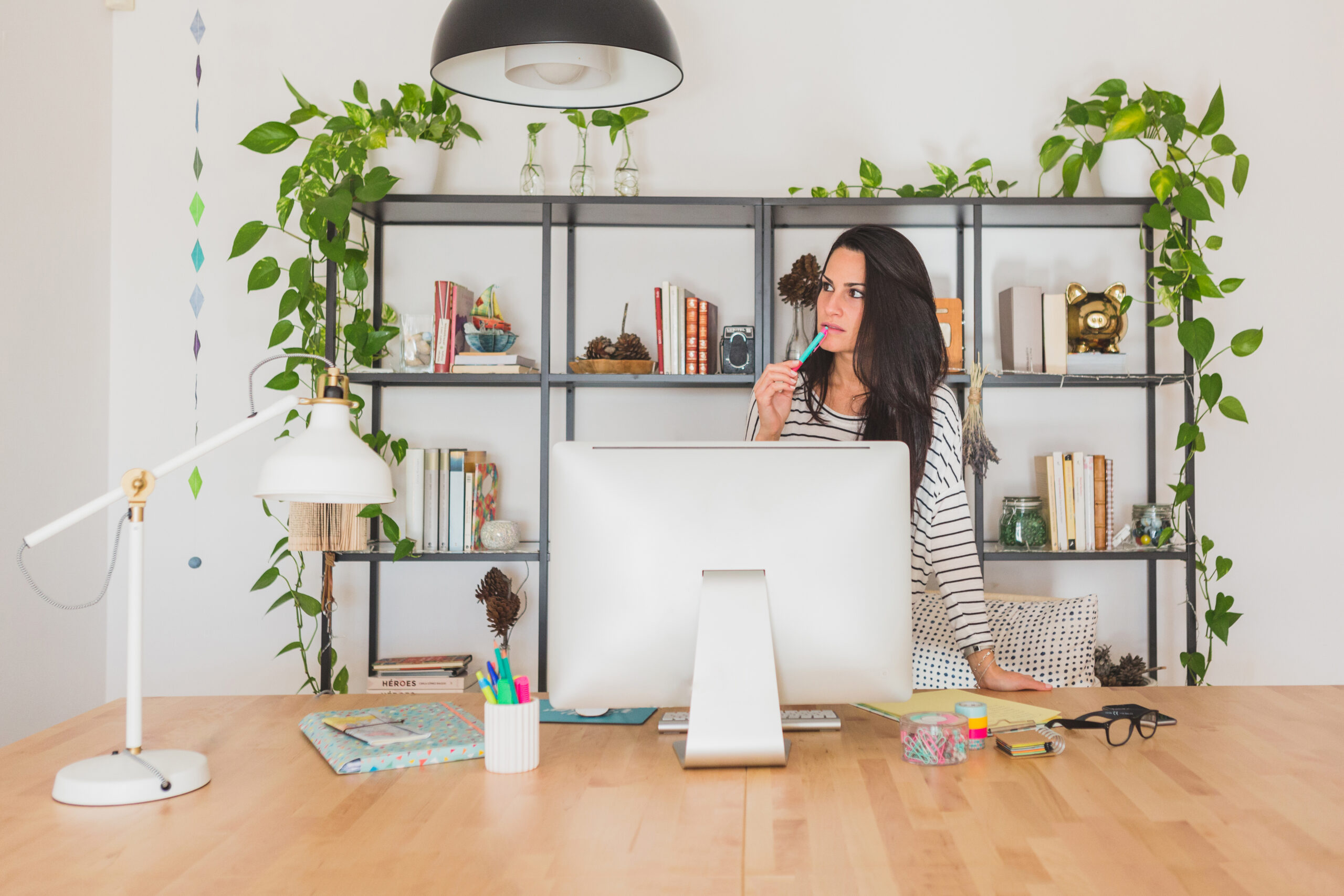 a woman thinking in her home office surrounded by beautiful desk accessories